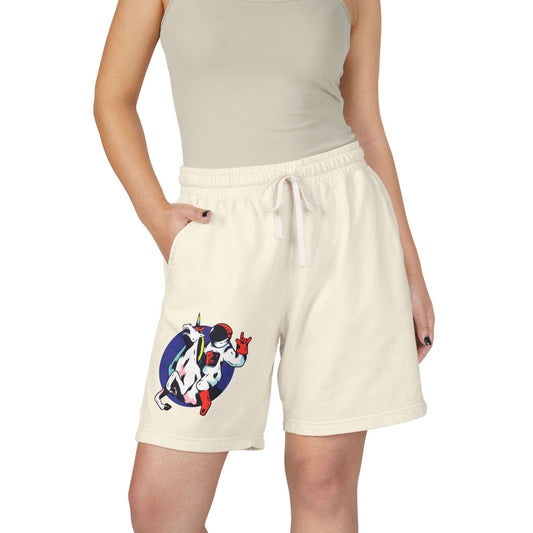 A model wearing cream-colored drawstring shorts with a colorful astronaut graphic on the left leg, paired with a matching ribbed tank top against a plain white background. Shop Comfort Colors Astronaut Unicorn Sweat Shorts Casual Wear for a fun, relaxed look that brings cozy comfort and standout style to your rotation. Buy Comfort Colors Astronaut Unicorn Sweat Shorts—soft, playful lounge essentials with a cosmic design made for everyday comfort. Purchase Comfort Colors Astronaut Unicorn Sweat Shorts.
