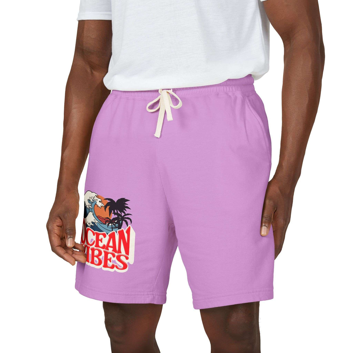 A person wearing lavender-purple drawstring shorts with a graphic print on the left leg that reads 'Ocean Vibes' with a rooster and wave illustration, paired with a white t-shirt against a plain white background. Unique Lightweight Fleece Sweat Shorts in Ocean Vibes Graphic Shop Lightweight Fleece Sweat Shorts in Ocean Vibes for breezy comfort, relaxed style, and an easygoing summer-ready look all day. Refresh your casual rotation with Lightweight Fleece Sweat Shorts in Ocean Vibes—soft, versatile.