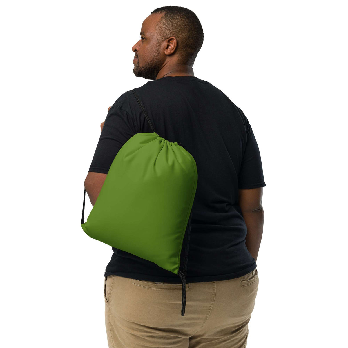 A man wearing a black t-shirt and khaki pants, shown from the back and side, carrying a bright green drawstring gym bag over his shoulder against a solid white background. Durable Minimalist Bold Solid Olive Drab Drawstring Bag