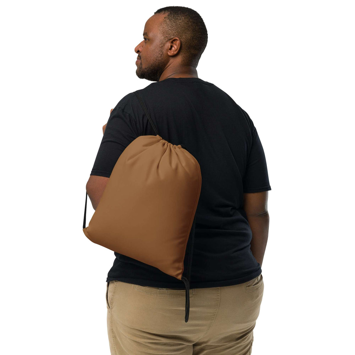 A man wearing a black t-shirt and khaki pants is shown from the back, carrying a large brown drawstring storage bag over his shoulder against a solid white background. Lightweight Bold Minimalist Solid Natural Wood Drawstring Bag