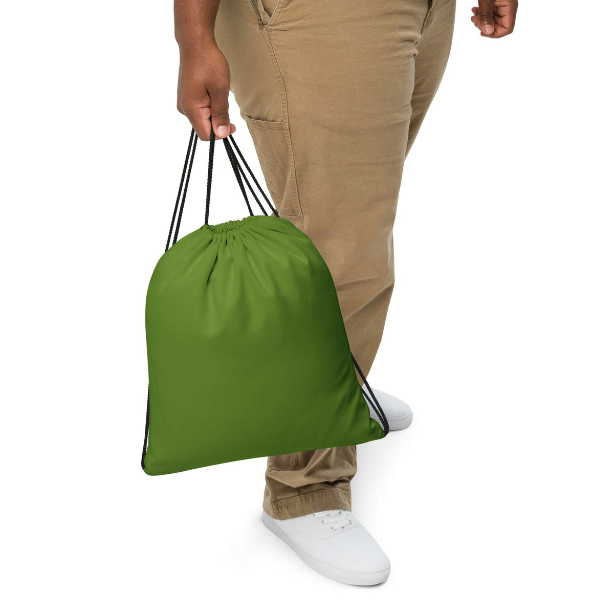A person wearing khaki pants and white sneakers holds a bright green drawstring bag against a plain white background. Lightweight Minimalist Bold Solid Olive Drab Drawstring Bag