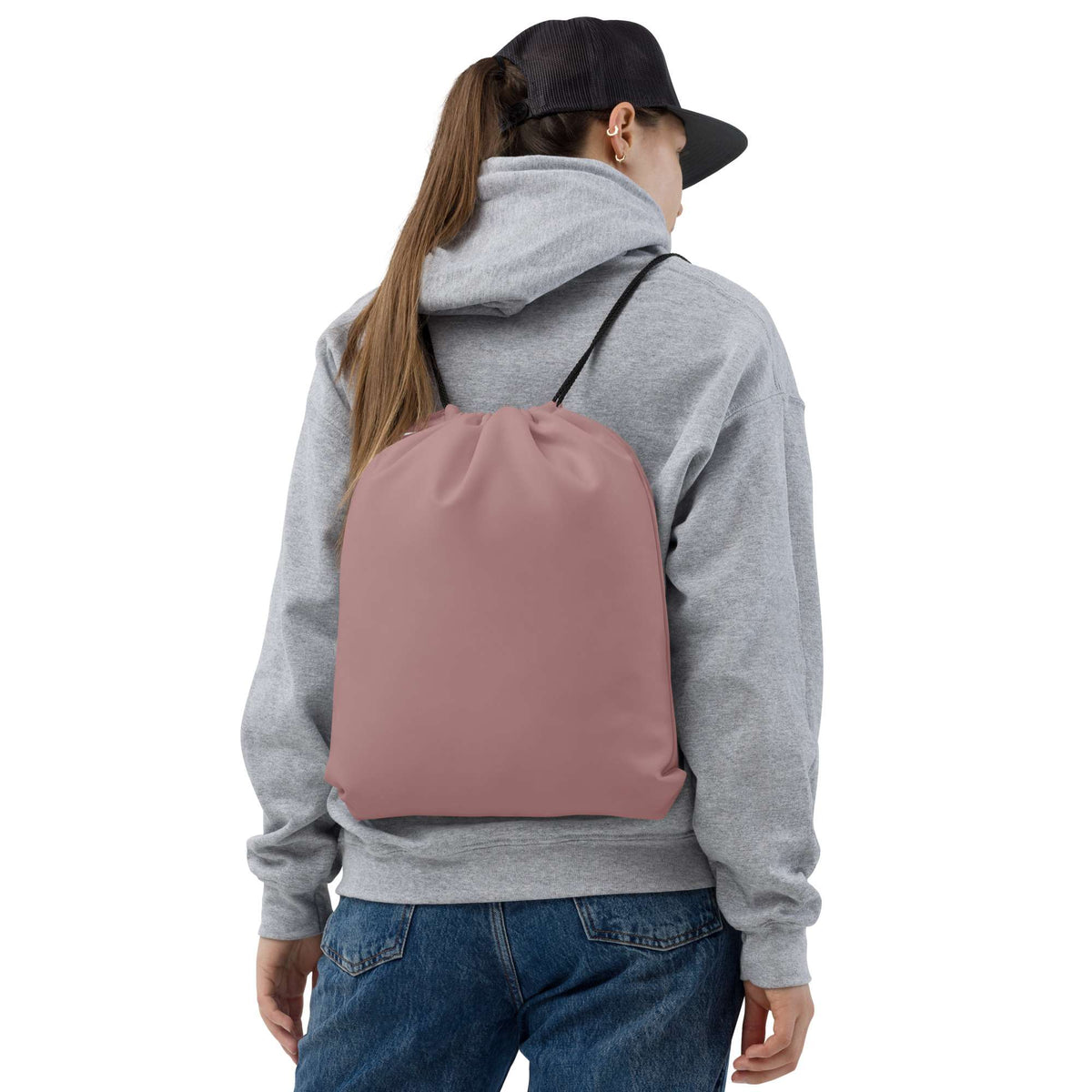 A person shown from the back wearing a dusty rose drawstring backpack over a gray hoodie and blue jeans, against a plain white background. Minimalist Solid Rosy Brown Durable Drawstring Bag