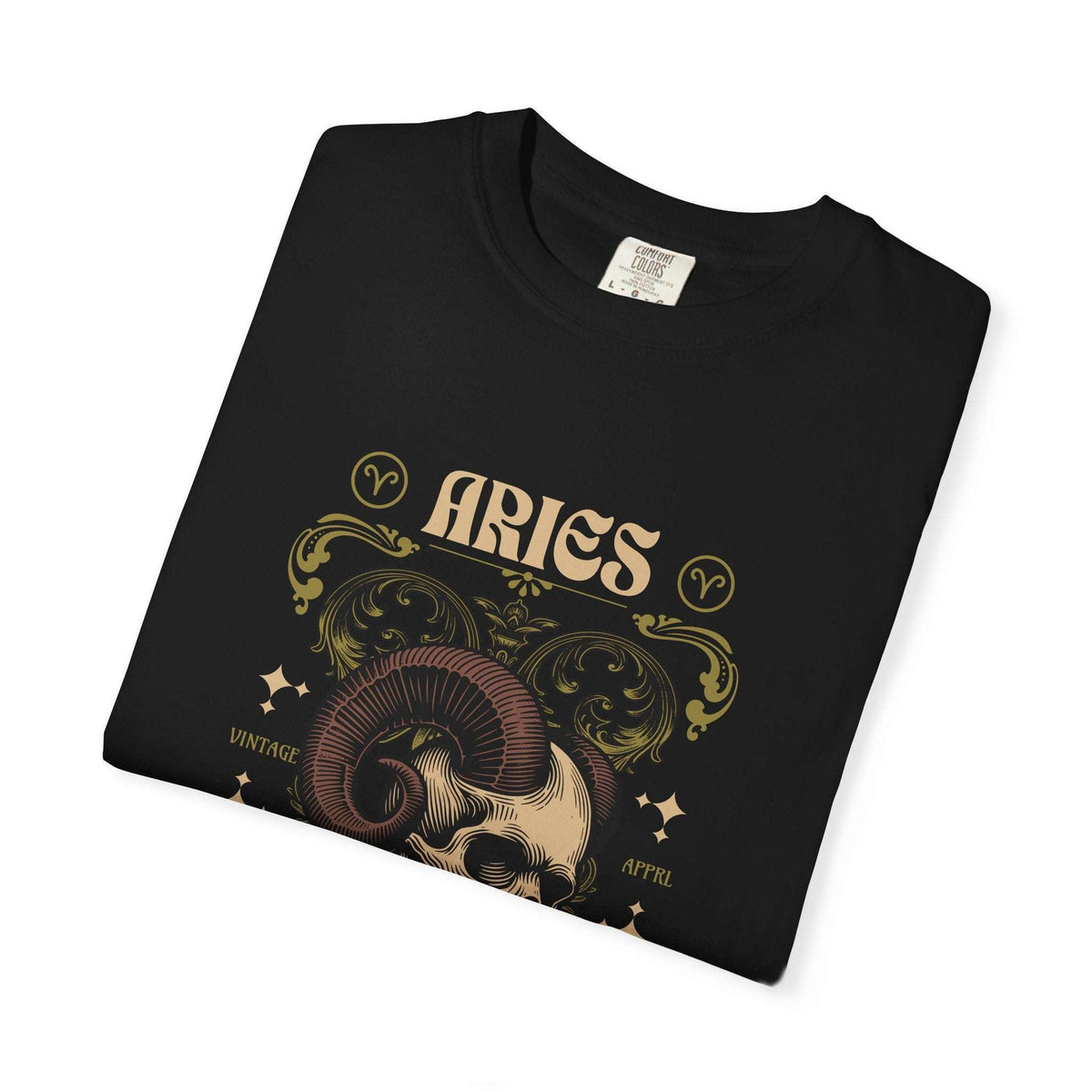 A folded black t-shirt with a vintage-style Aries zodiac graphic featuring a ram skull, ornate gold and beige scrollwork, and the word 'ARIES' on a white background.