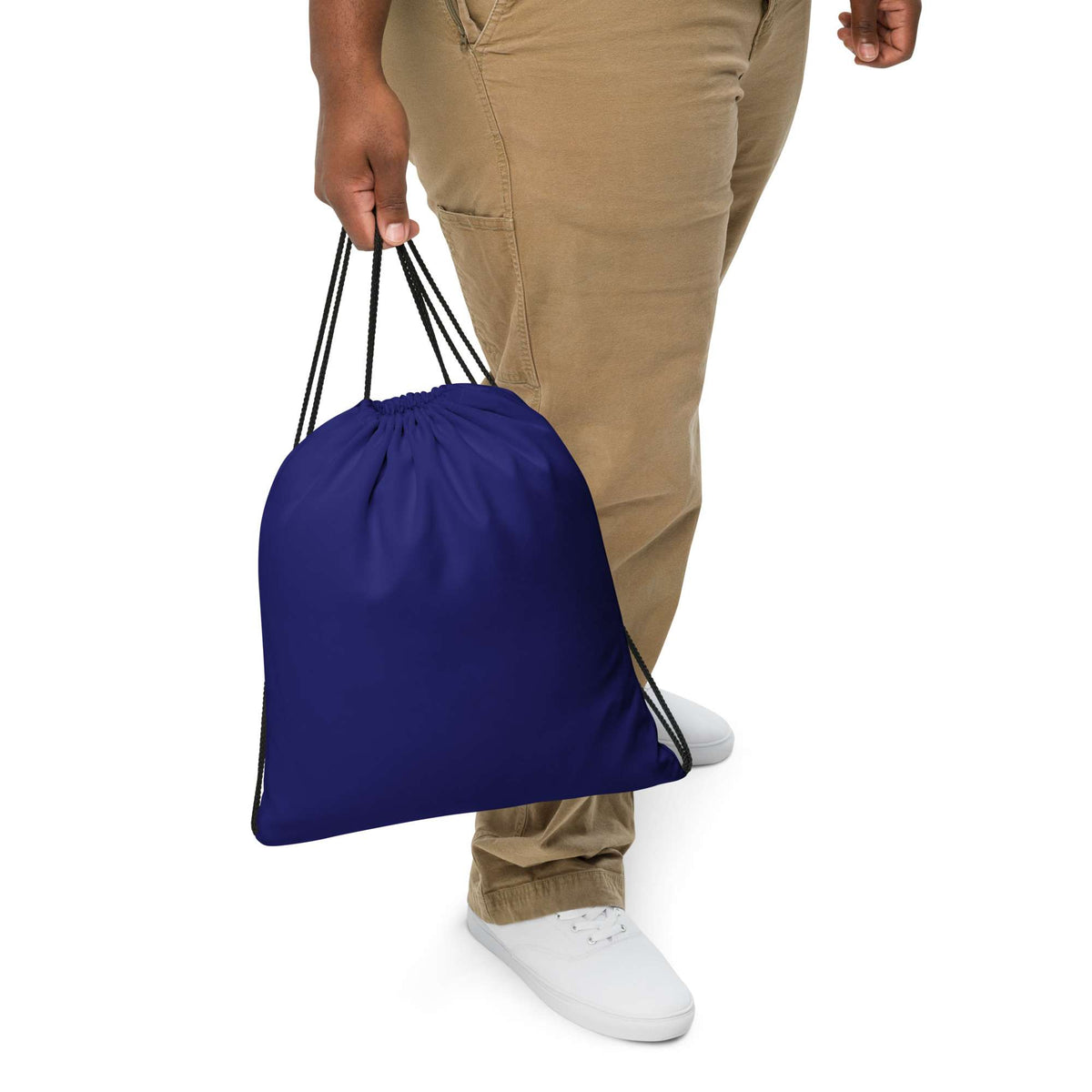 A person wearing khaki pants and white sneakers holds a royal blue drawstring bag against a plain white background. Versatile Bold Minimalist Solid Midnight Blue Drawstring Bag
